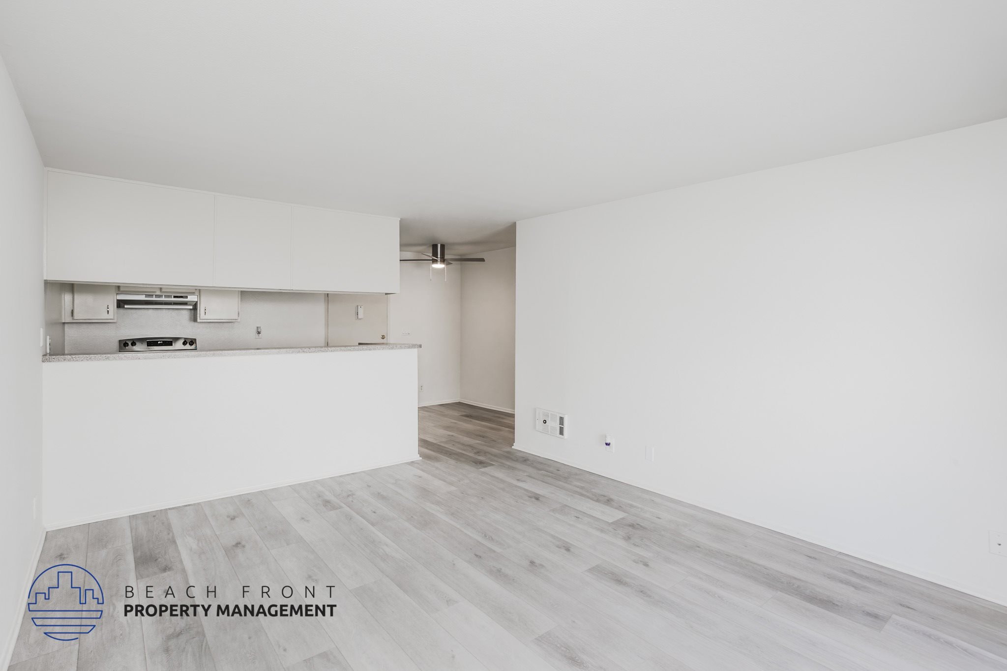 A spacious room with a logo for Beach Front Property Management in the bottom left corner.