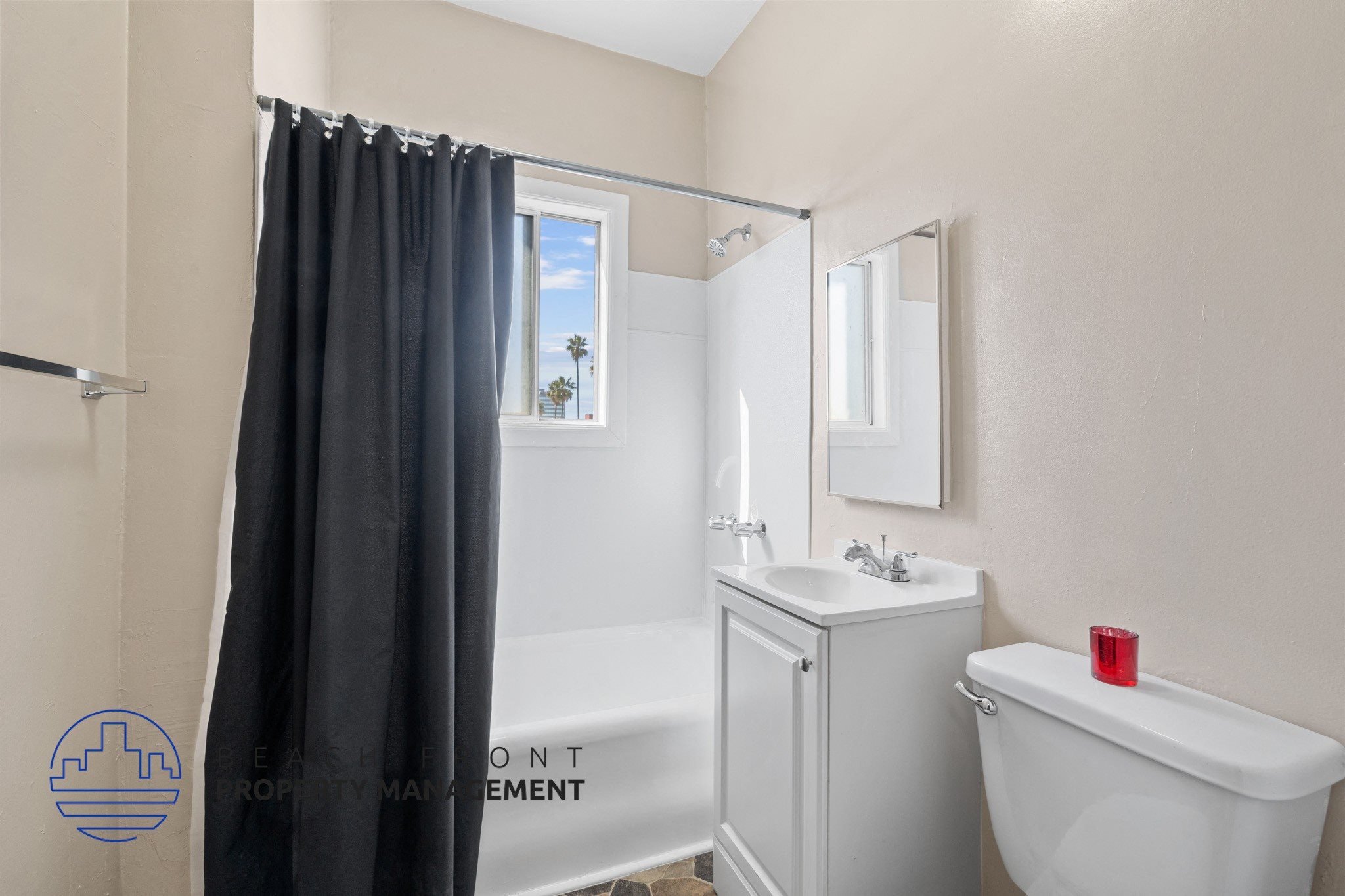 A bathroom with a white tub, sink, and a window with a black curtain.
