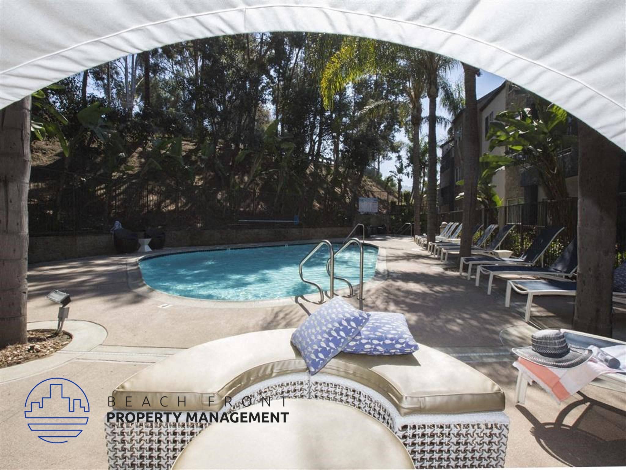 A pool area with a white canopy and a pool chair with a blue and white pillow on it.