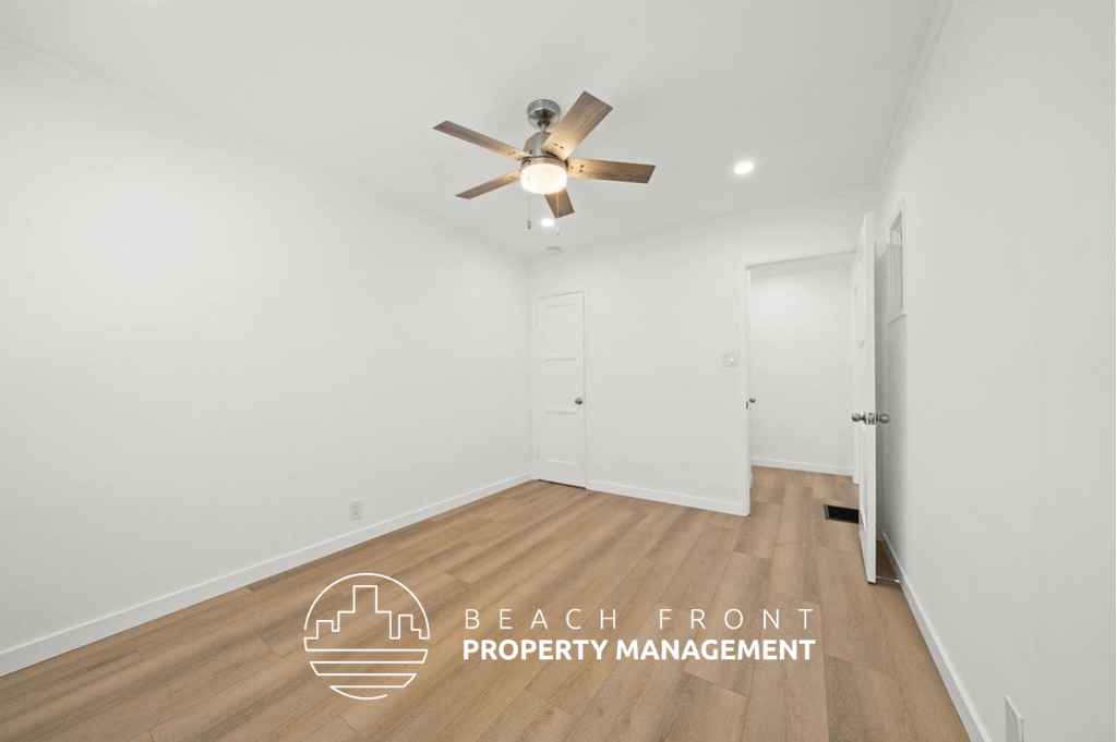 a living room with white walls and a ceiling fan