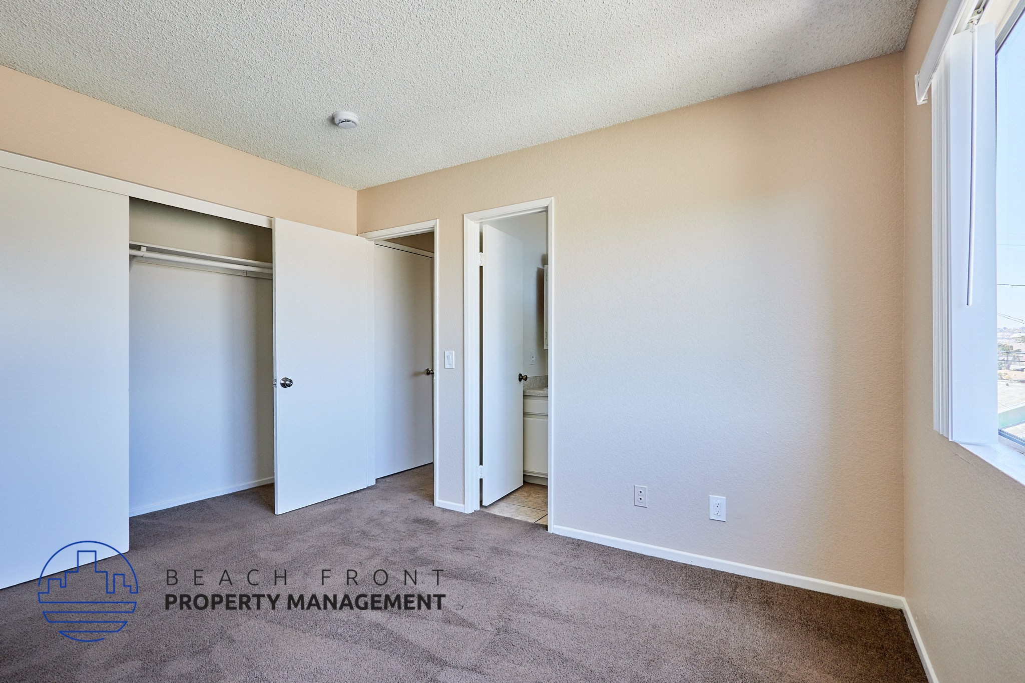 A room with a carpeted floor and a window on the right side.