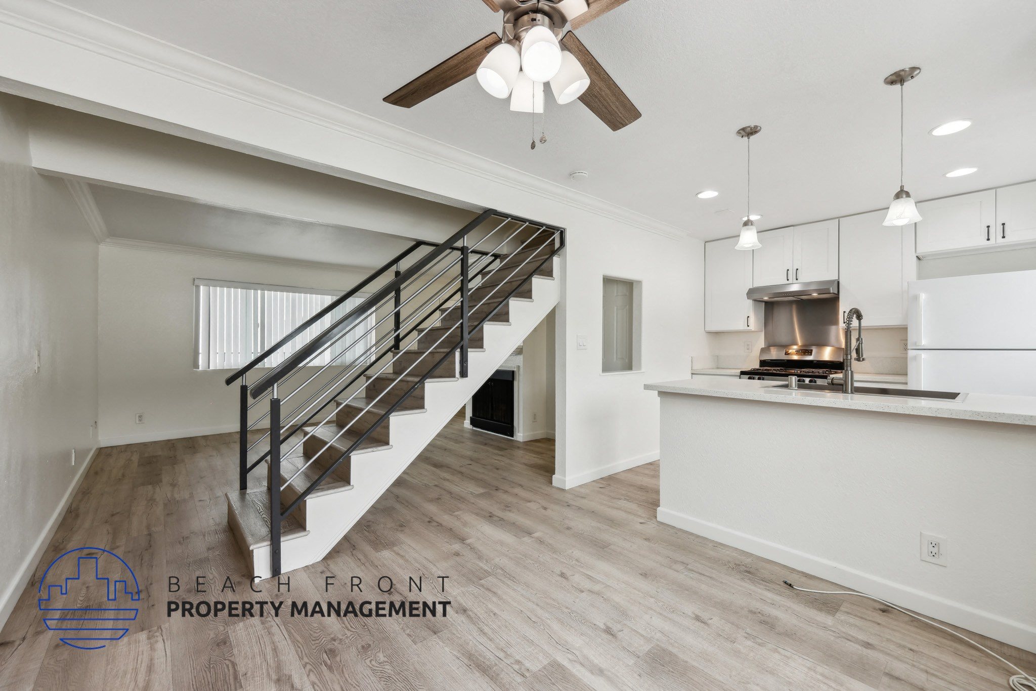 A spacious room with a staircase and a kitchen area.