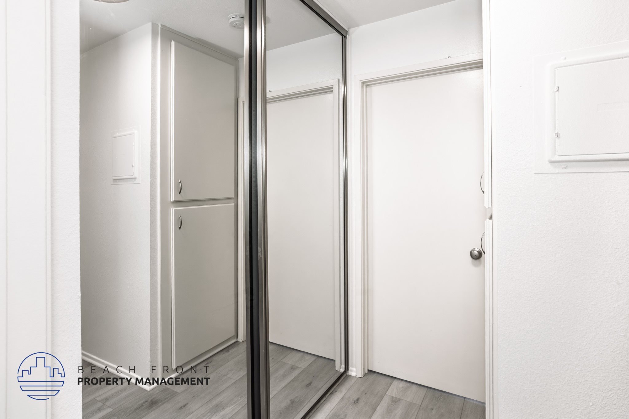 A white door is in a room with a mirror on the wall.