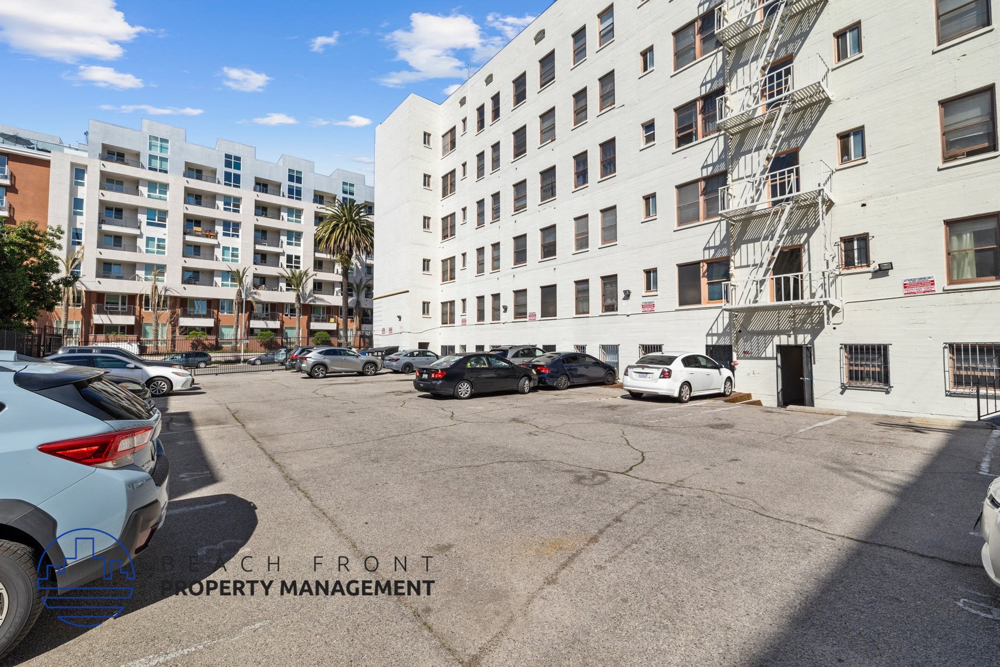 A parking lot with cars and a building with a fire escape.