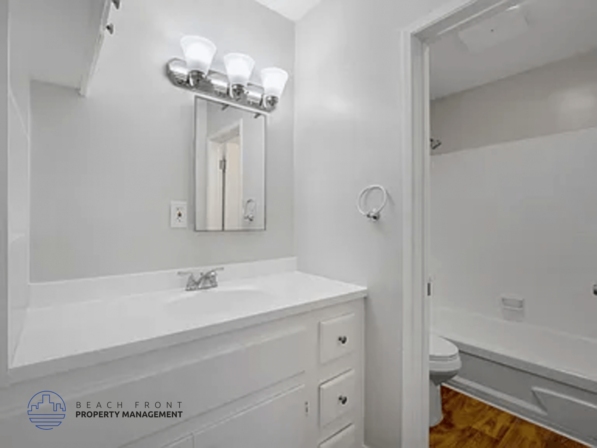 A white bathroom with a sink, mirror, and toilet.