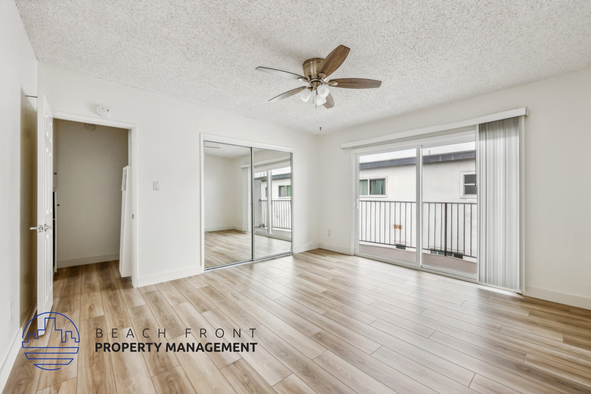 A spacious room with a ceiling fan and wooden flooring.
