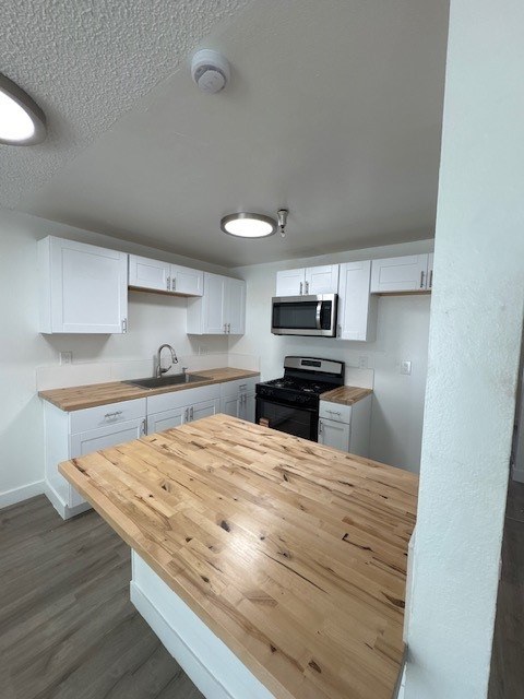 A kitchen with a wooden counter top and white cabinets.