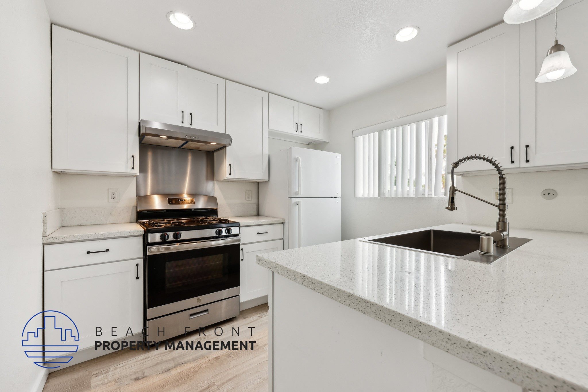 A modern kitchen with white cabinets and a stainless steel sink.