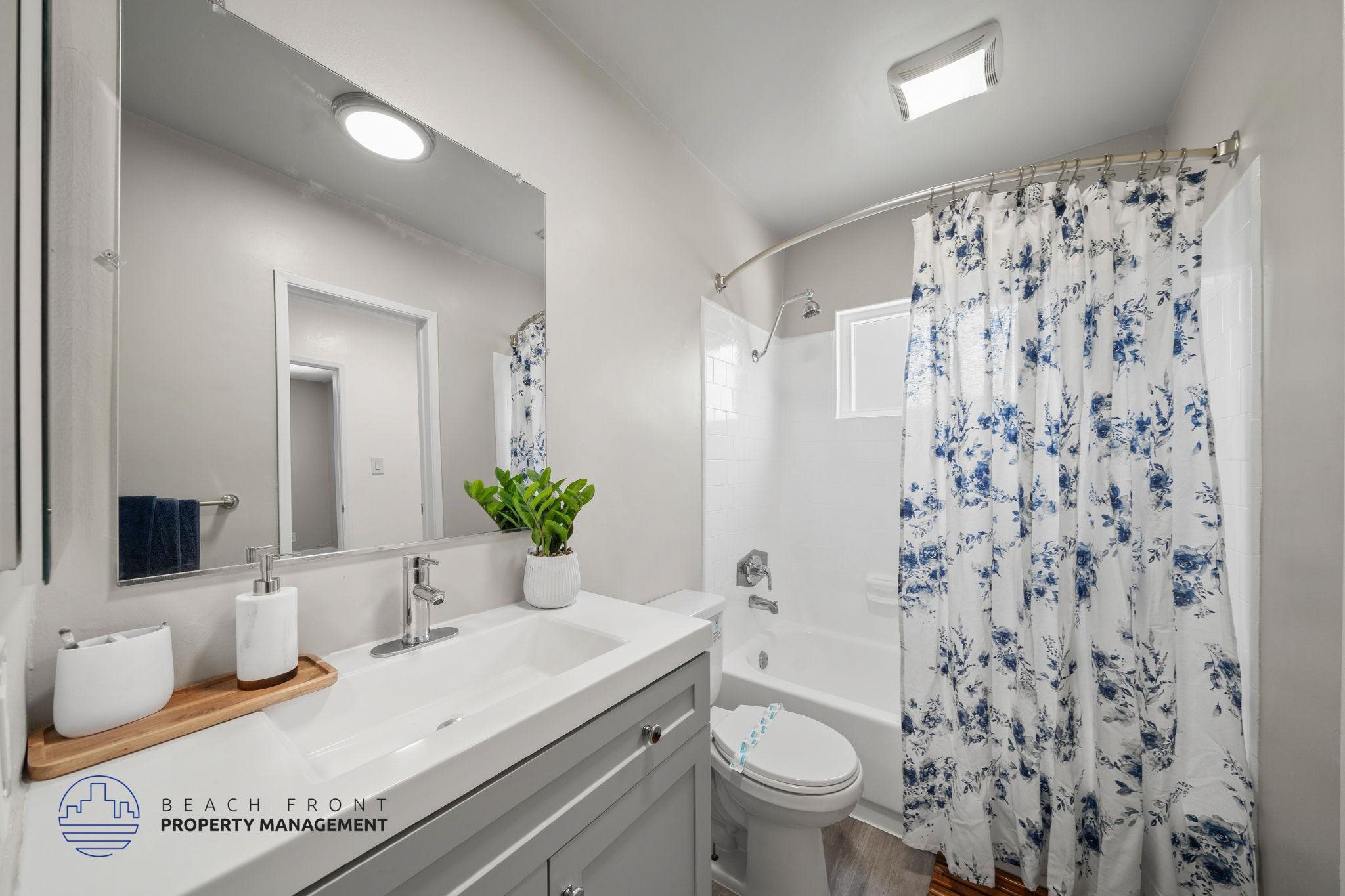 A bathroom with a white sink, toilet, and shower curtain.