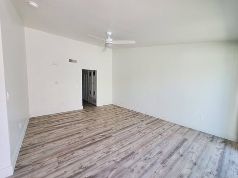 an empty living room with wood flooring and a ceiling fan