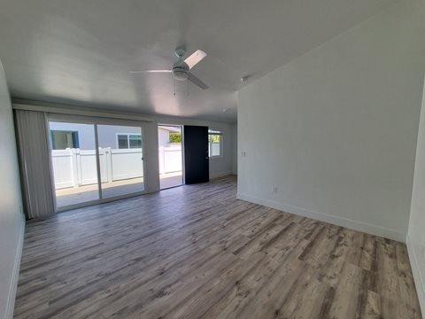 an empty living room with wood flooring and a ceiling fan