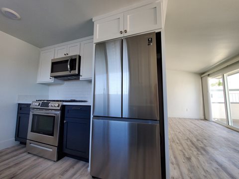 an empty kitchen with a stainless steel refrigerator and microwave