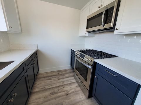 a kitchen with blue cabinets and a stove and a microwave