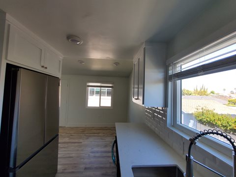 a kitchen with white cabinets and a large window