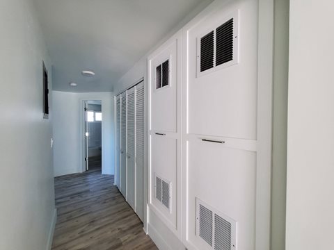 a long hallway with white doors and white walls and a wood floor