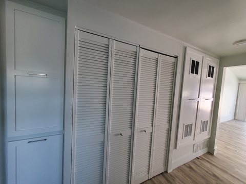 a row of closets in a hallway with blue walls and white shutters