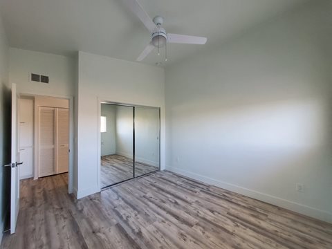 an empty living room with white walls and a ceiling fan