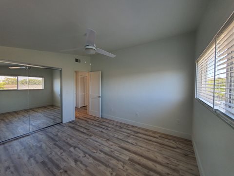 an empty living room with wood floors and a ceiling fan