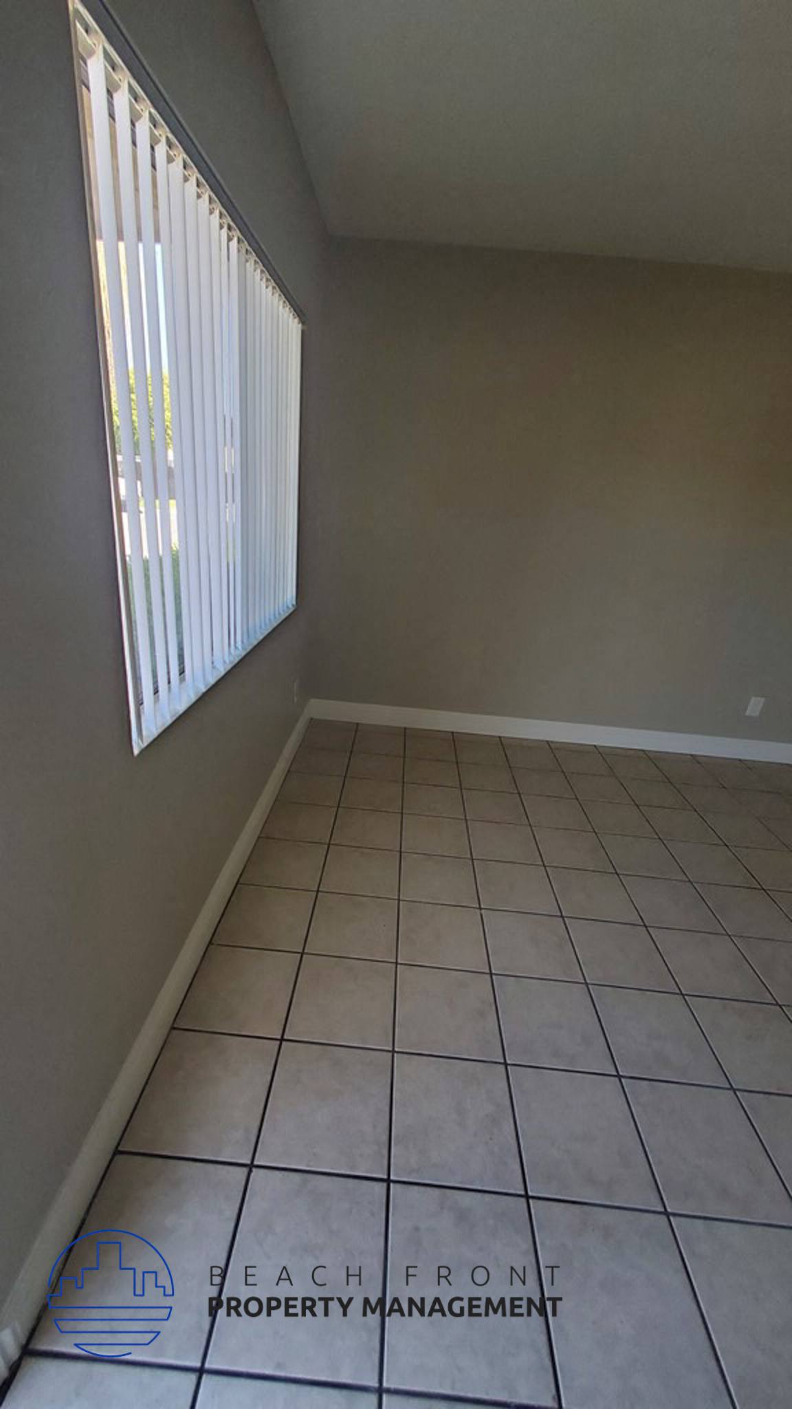 an empty room with a window and a tiled floor