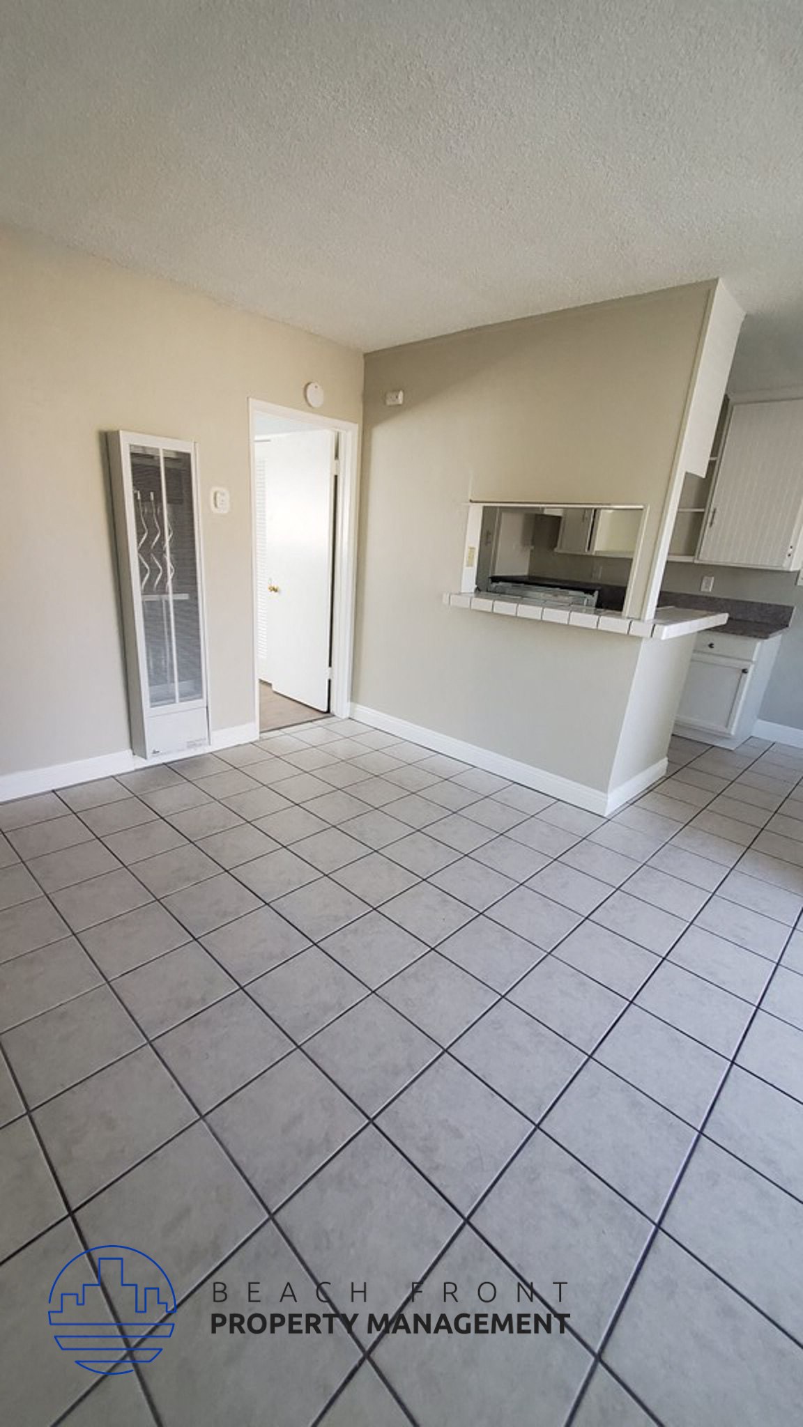 an empty kitchen and living room with a tiled floor