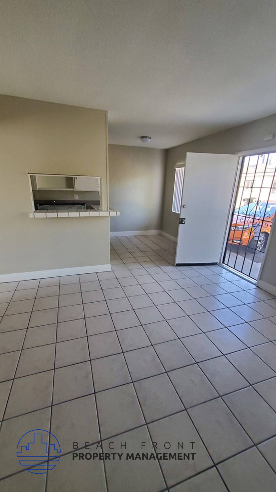 an empty living room with a tiled floor and a door