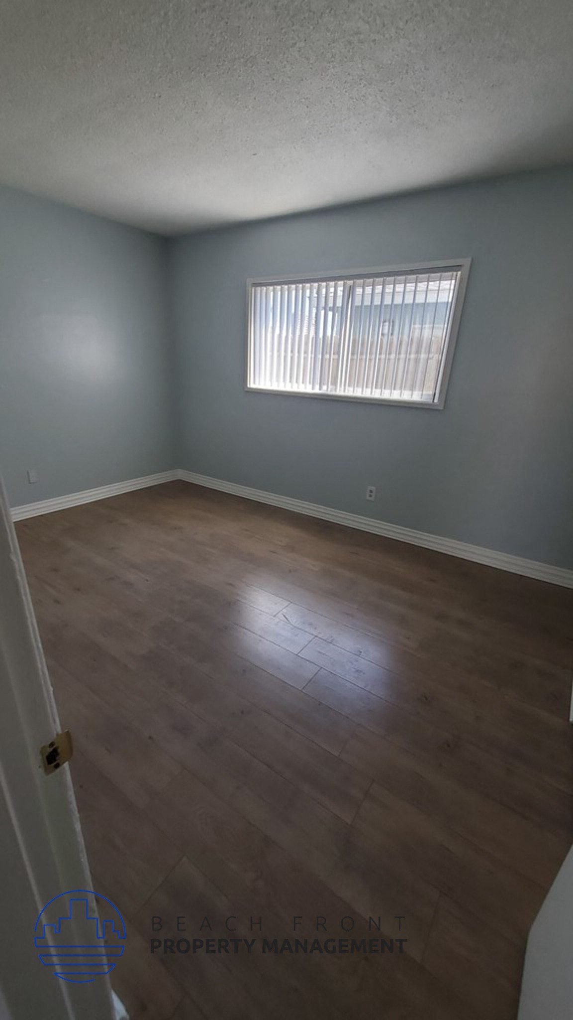 an empty living room with wood floors and a window