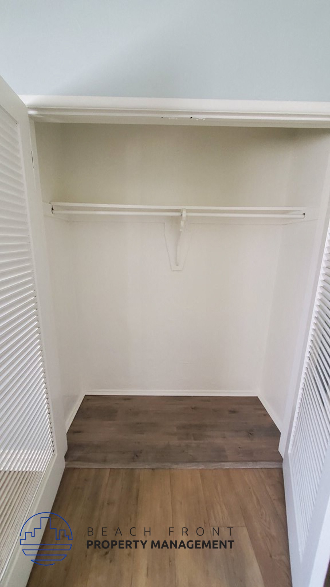 an empty closet with a wooden floor and a white shelf