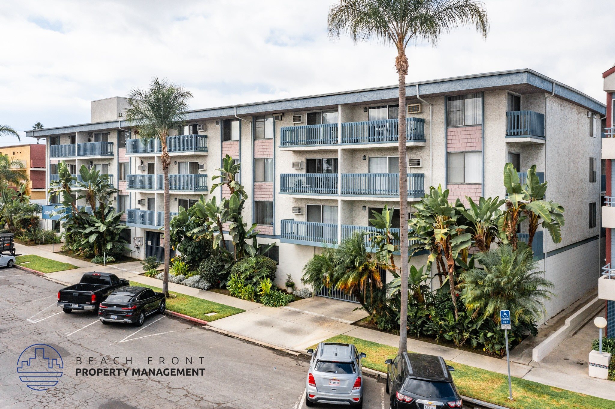 A building with balconies and palm trees in front.
