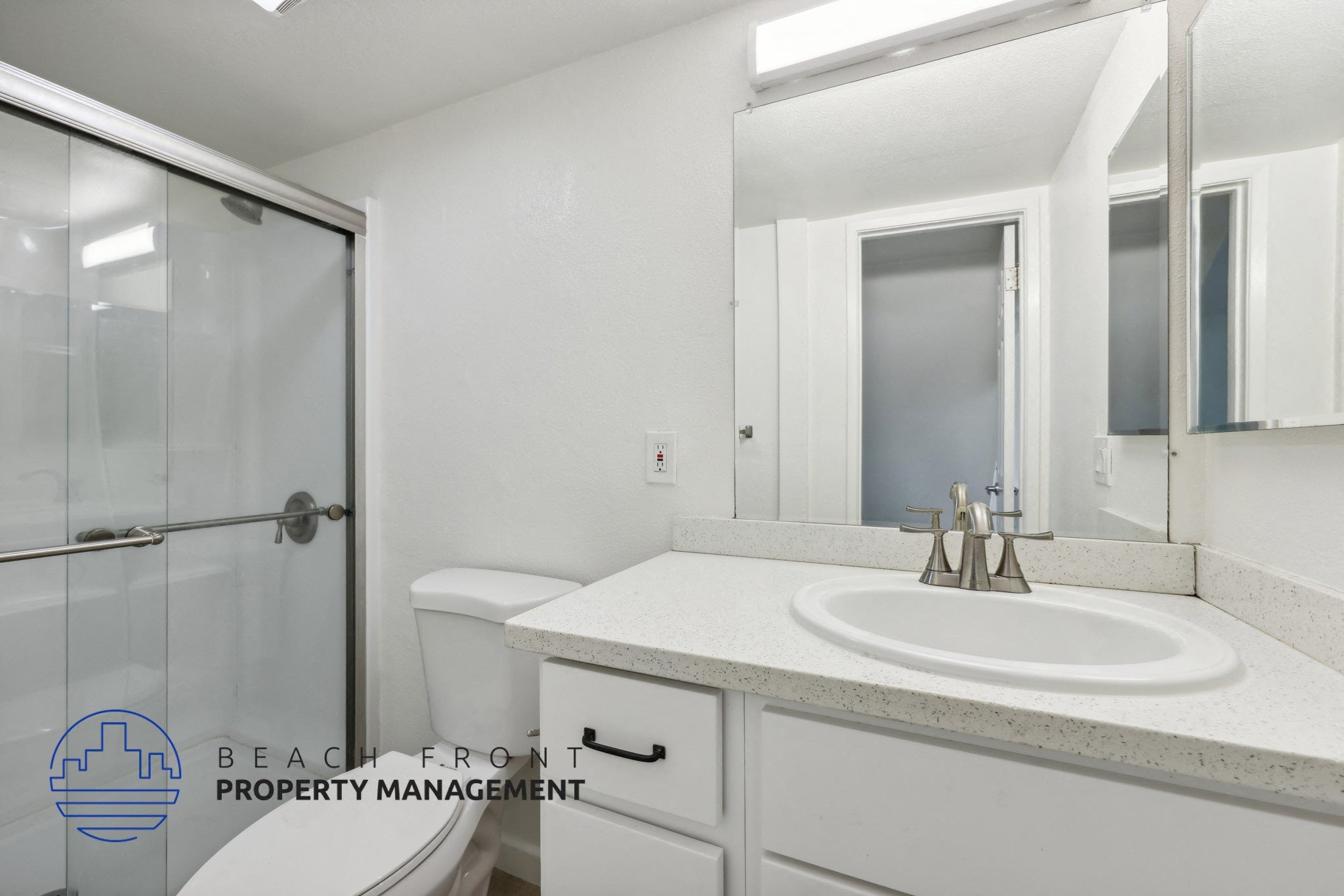 A bathroom with a sink, mirror, and shower.