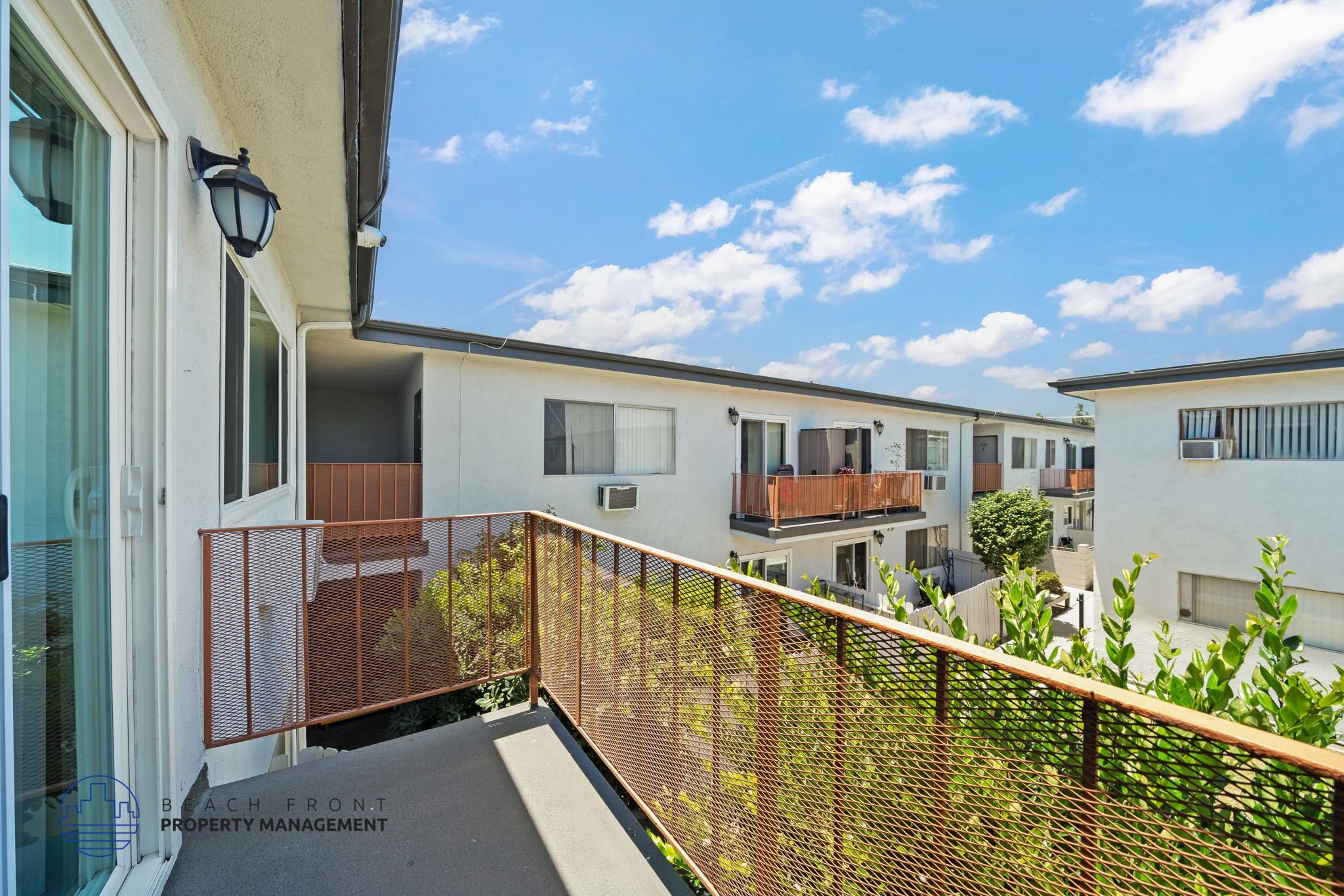 A balcony with a railing and a view of the sky and other buildings.