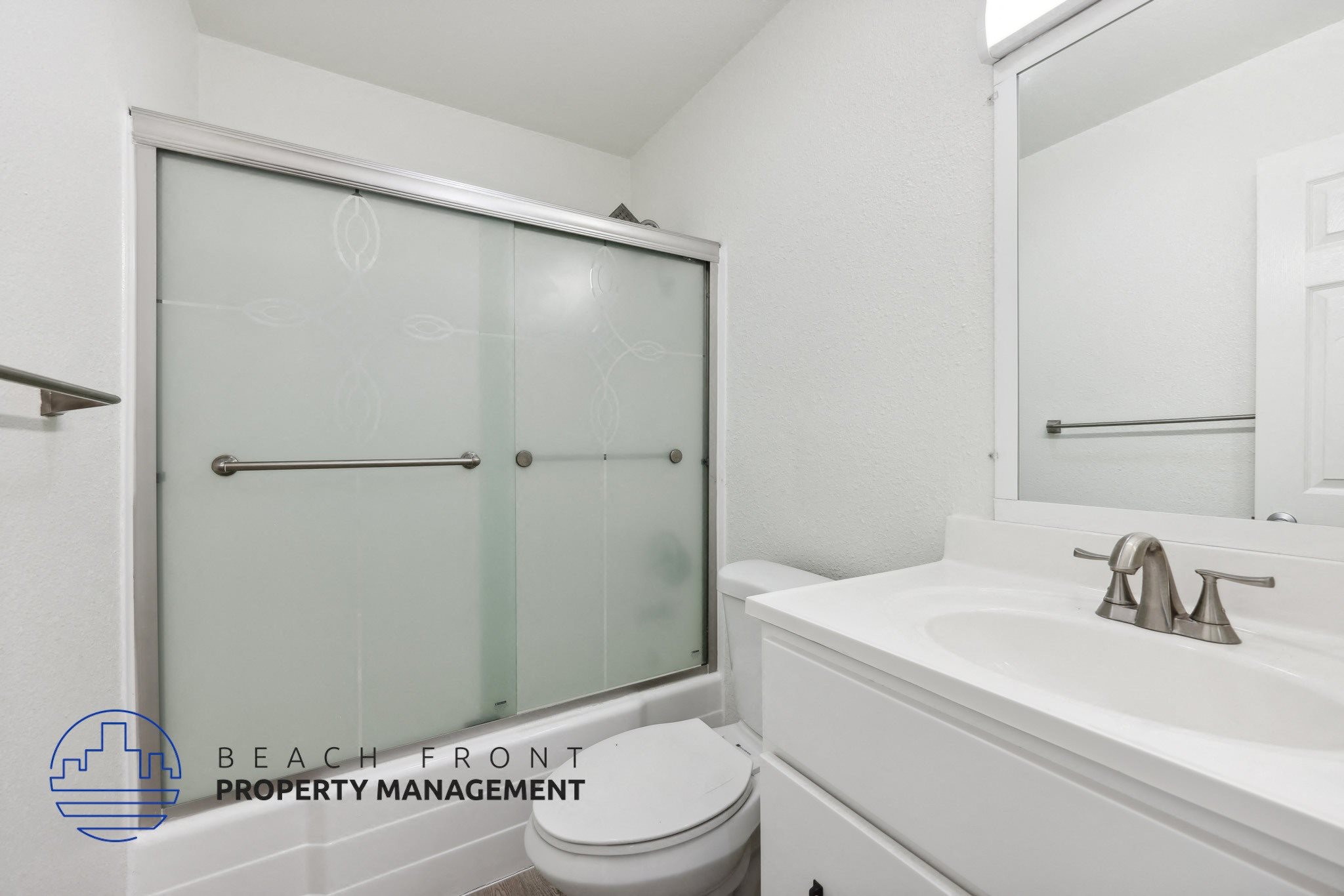A white bathroom with a toilet, sink, and shower.