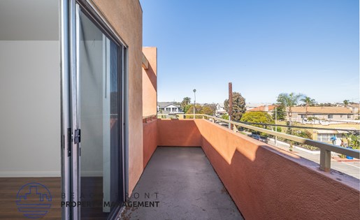 A balcony with a glass door and a view of the street below.