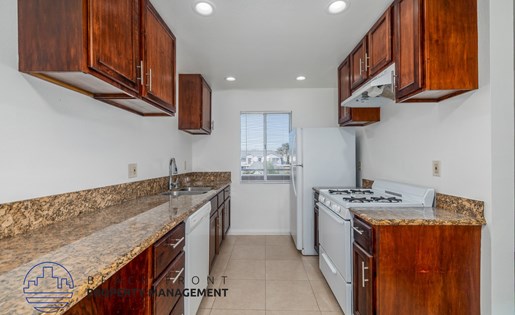 A kitchen with wooden cabinets and a granite countertop.