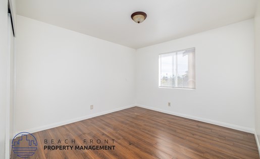 A room with wooden flooring and a window with blinds.