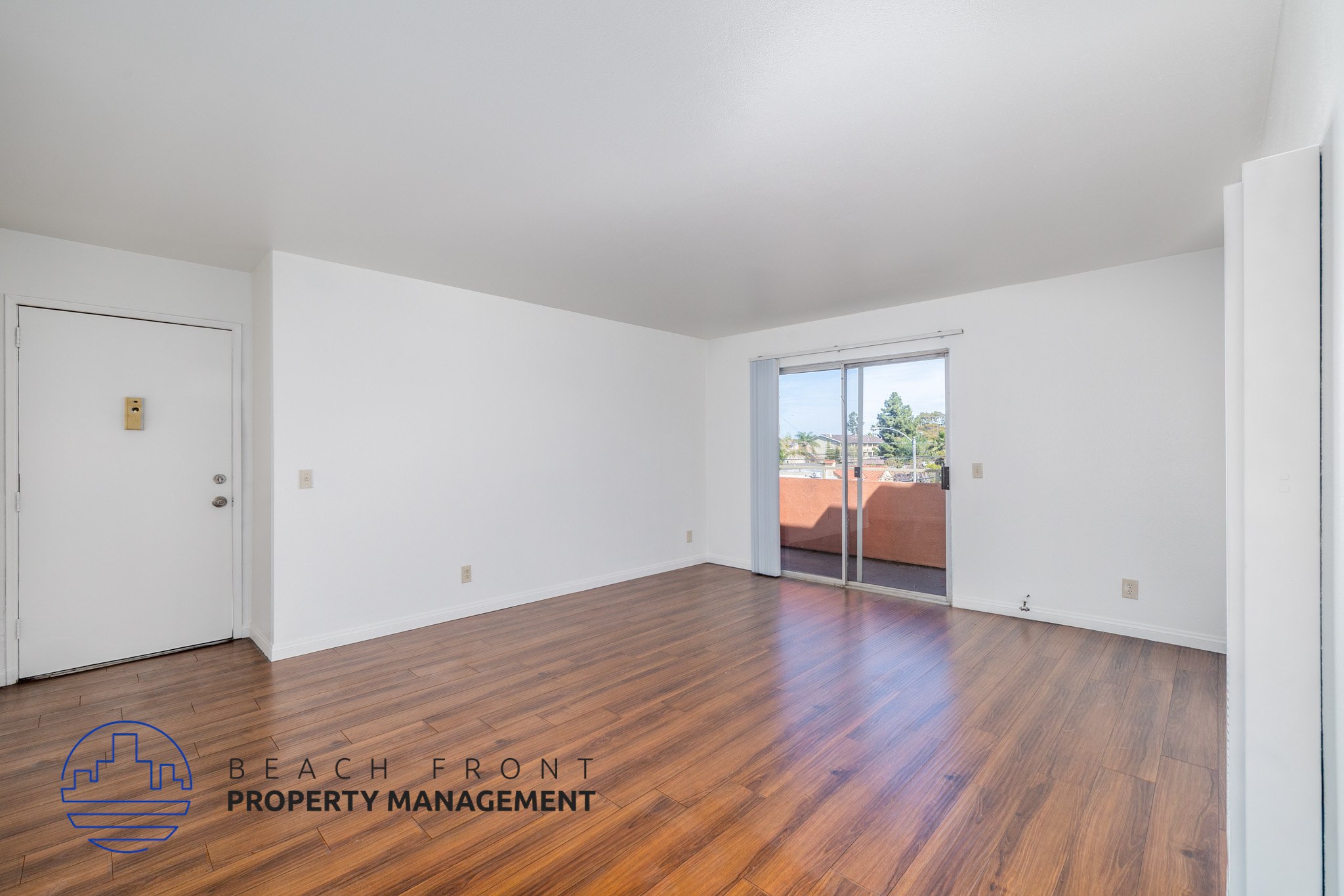 A room with wooden floors and a logo for Beach Front Property Management.