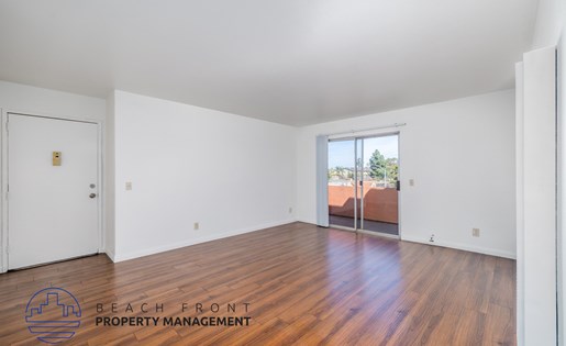 A room with wooden floors and a logo for Beach Front Property Management.