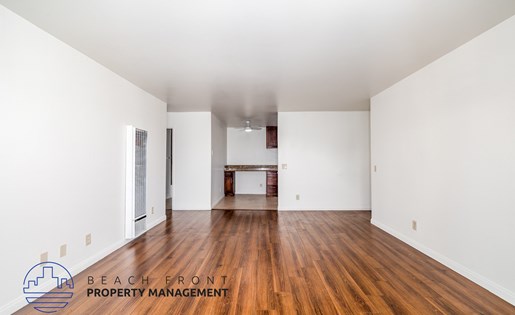 A spacious room with wooden floors and white walls.