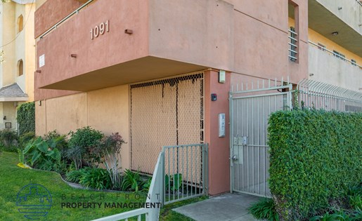 A building with the number 1091 on it is surrounded by a green lawn and a metal gate.