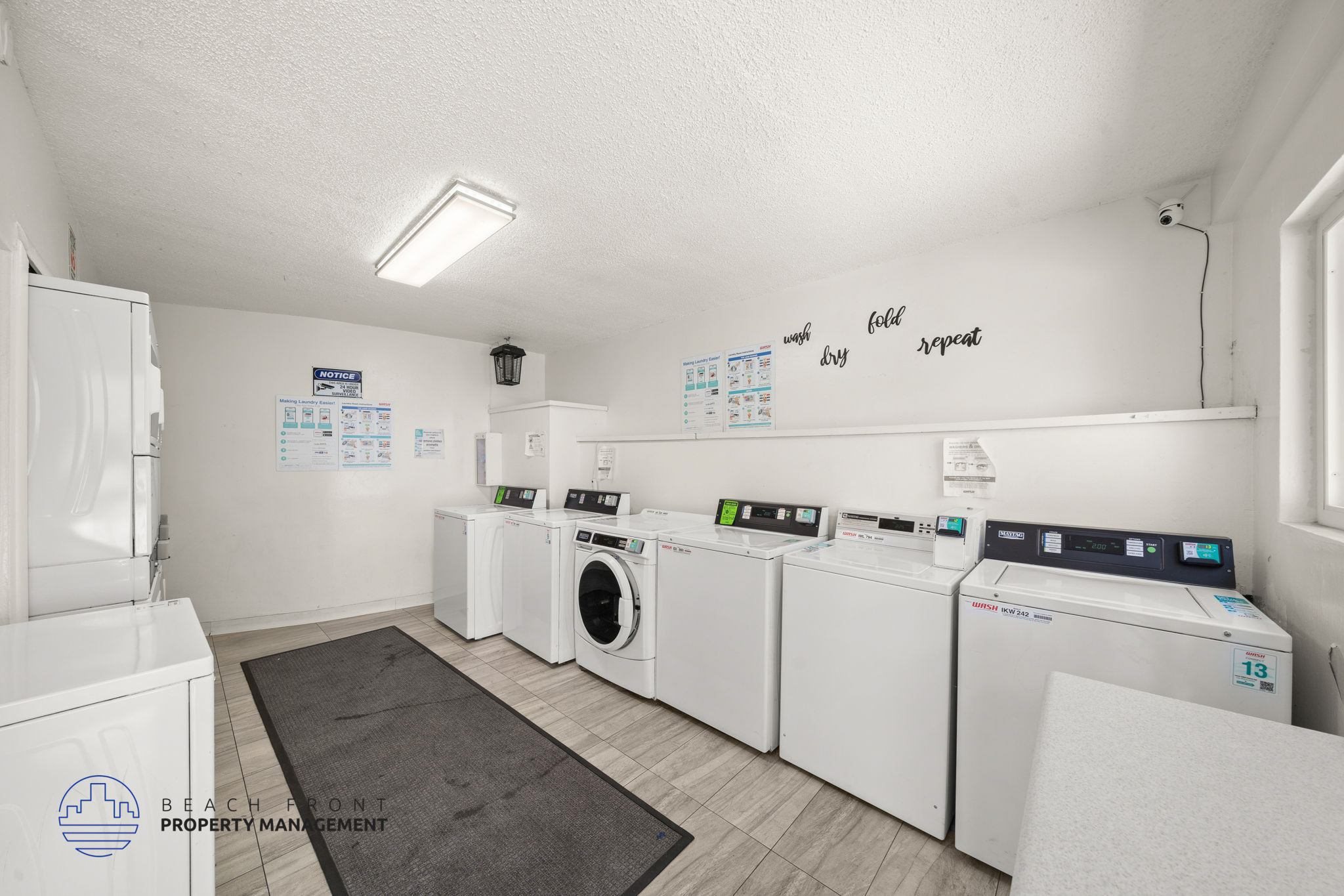 A laundry room with washers and dryers and a sign that says Beach Front Property Management.
