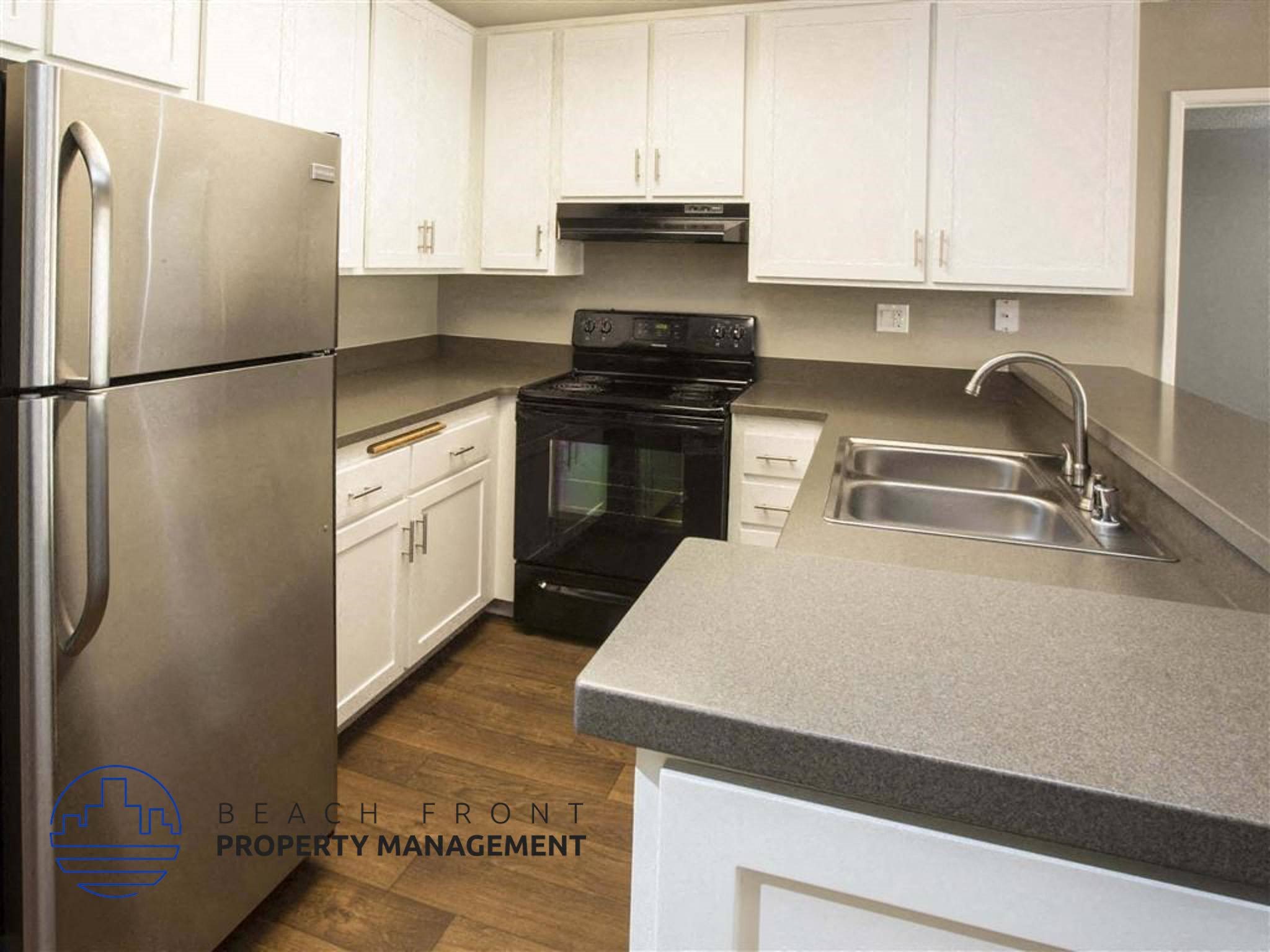 A kitchen with a stainless steel refrigerator and white cabinets.