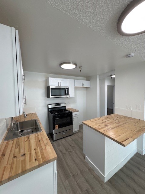 A kitchen with a wooden counter top and a white fridge.