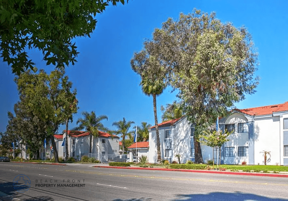A row of white houses with trees in front.