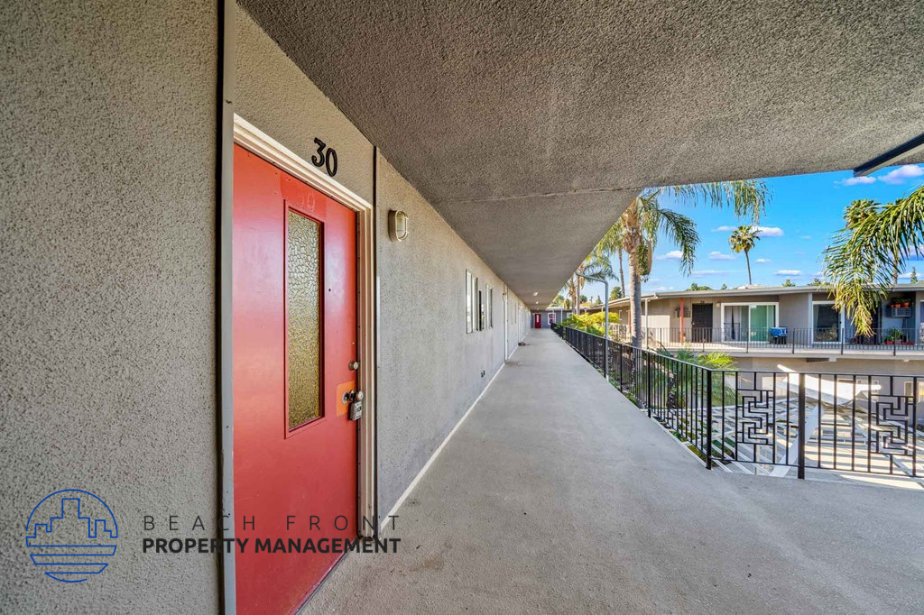 A red door with the number 30 on it is on the left side of a concrete wall.