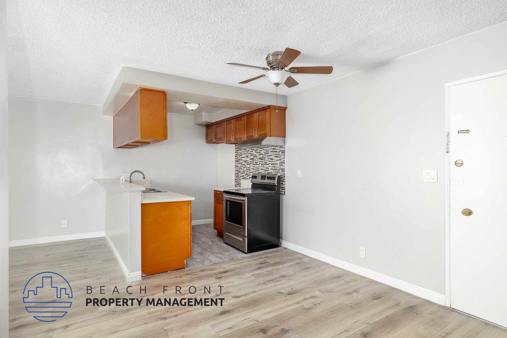 A kitchen area with a white ceiling fan and wooden cabinets.