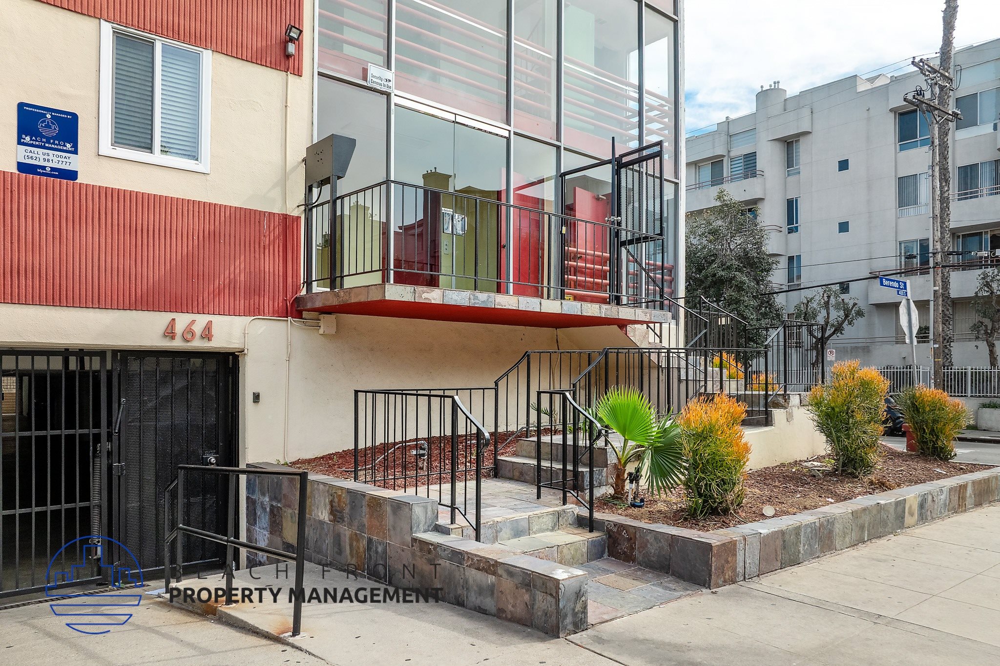 A building with a red and white facade has a balcony with a black railing.