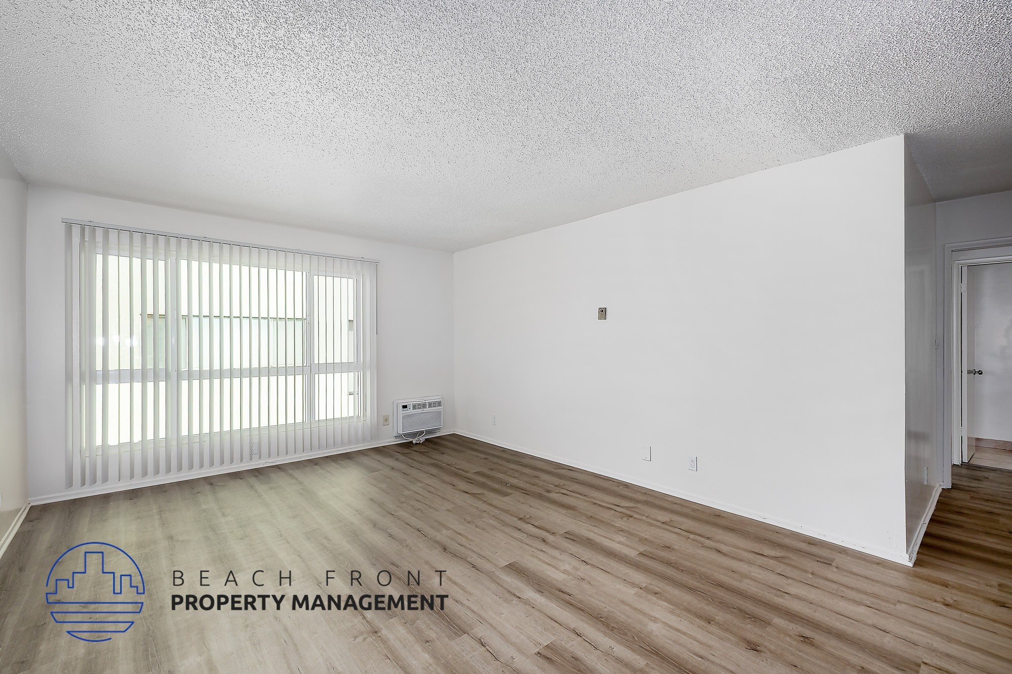 A room with wooden flooring and a window with blinds.