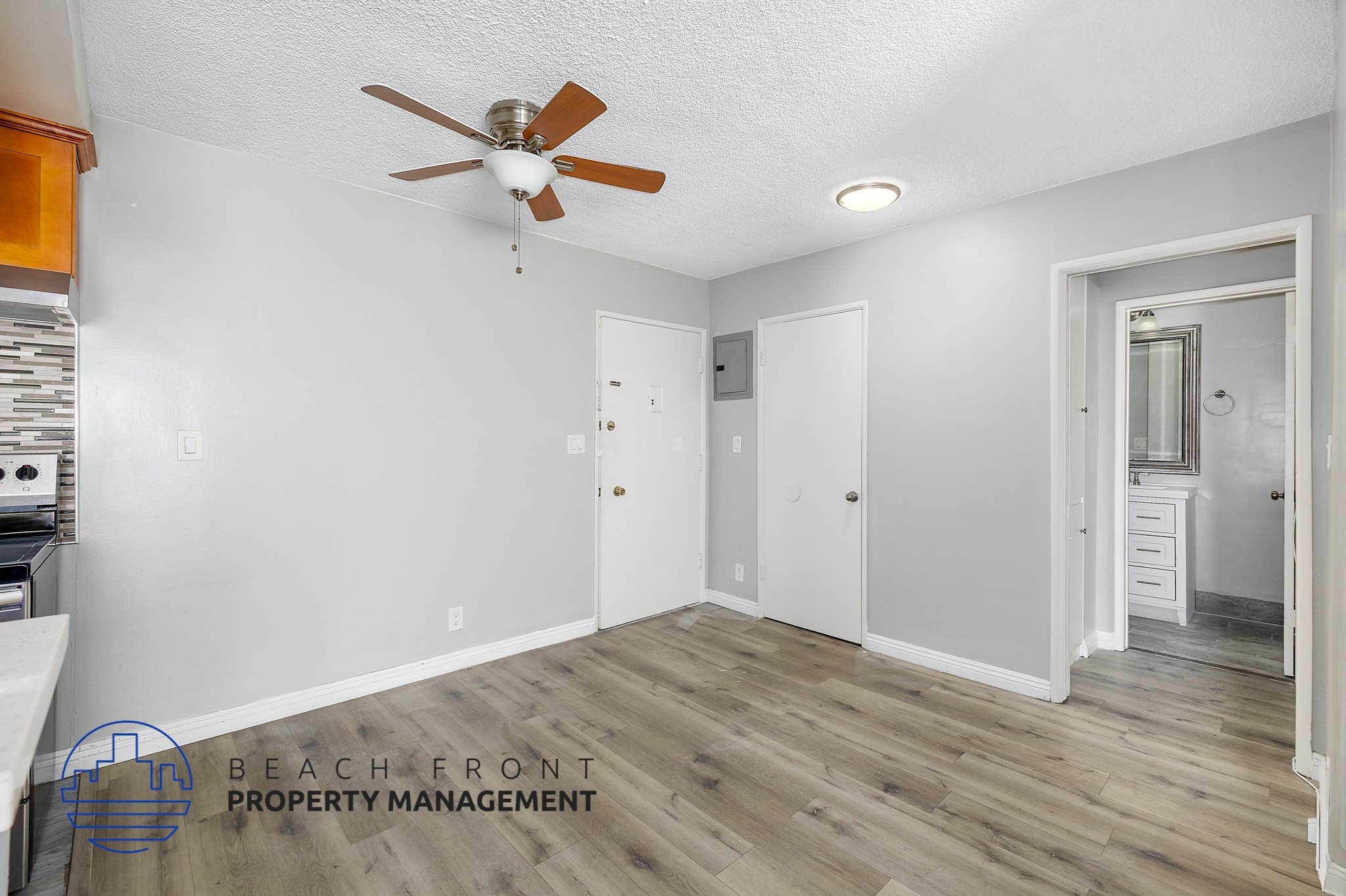 A room with a ceiling fan and wooden flooring.