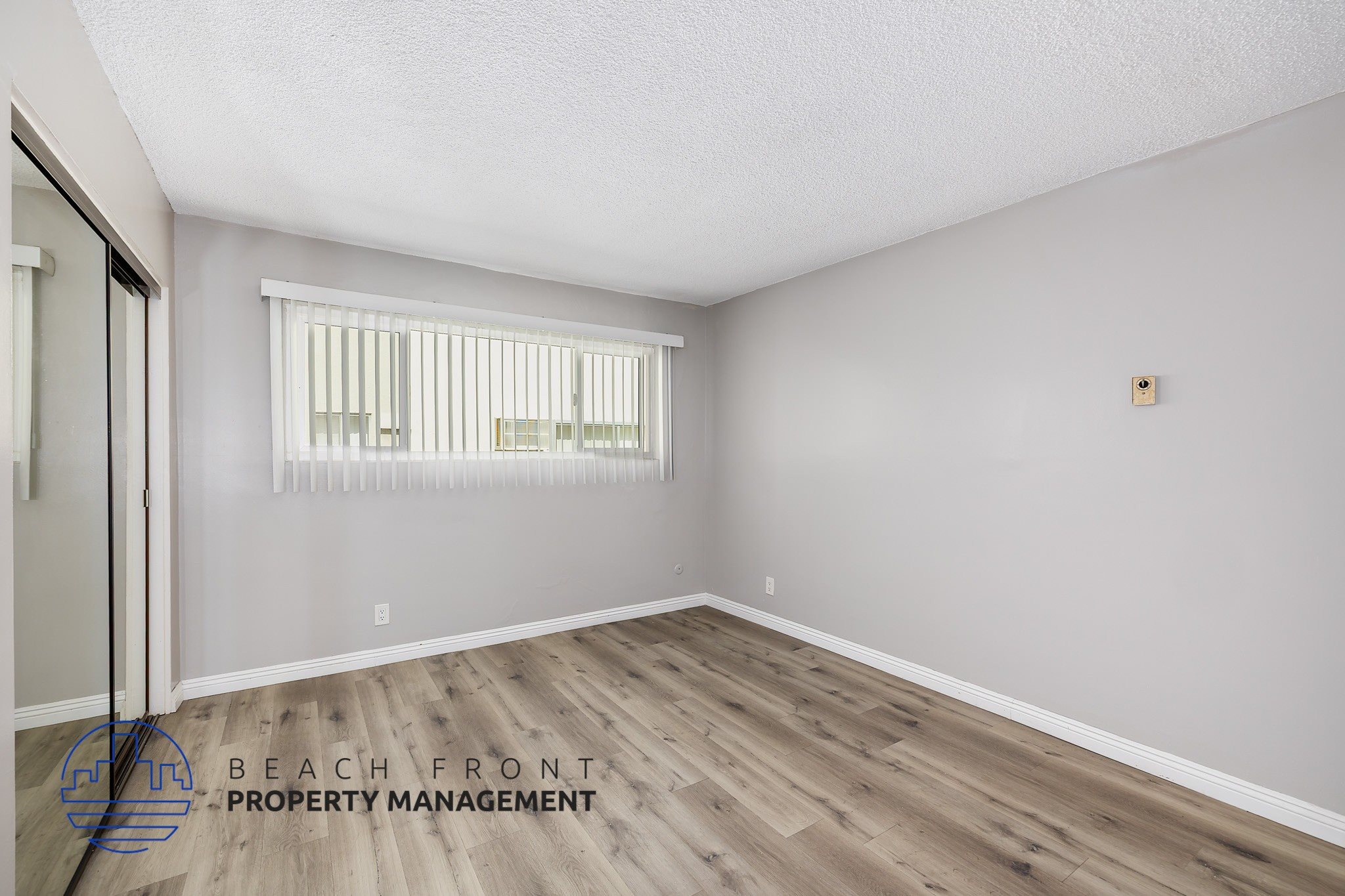 A room with wooden flooring and a window with blinds.