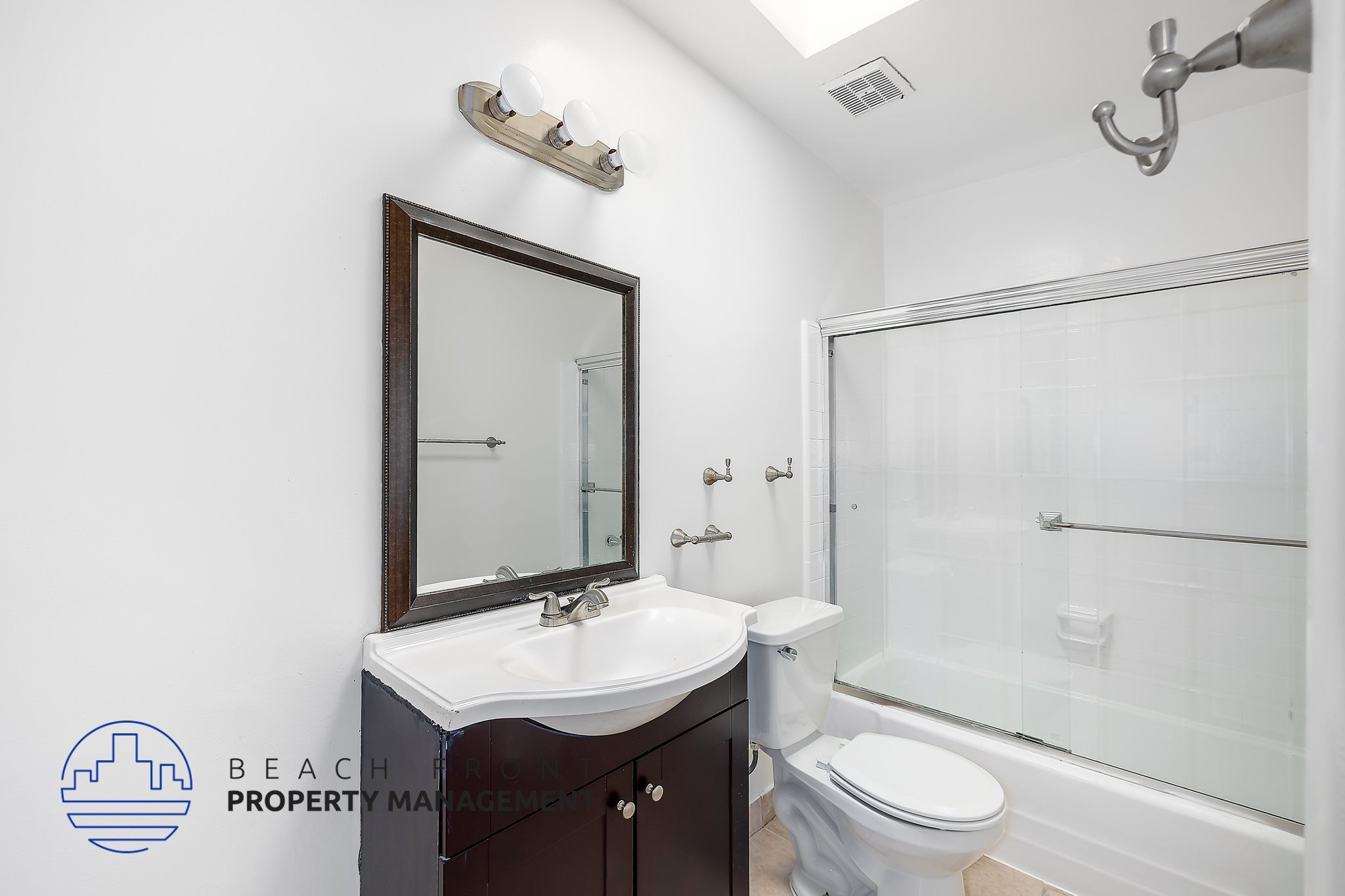 A bathroom with a sink, mirror, toilet and bathtub.