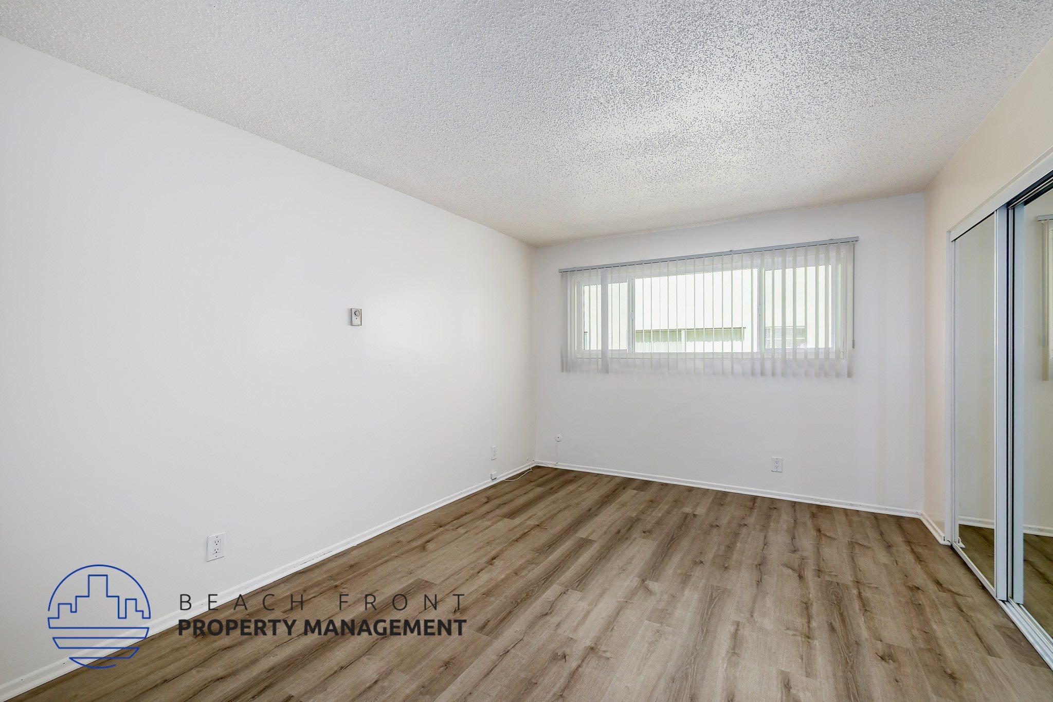 A room with wooden flooring and a window with blinds.
